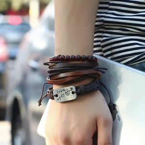 Close-up of multilayer leather bracelet with Love metal plate on a male wrist