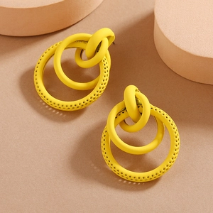 Close-up of bright yellow interlocking triple hoop earrings with perforated texture details