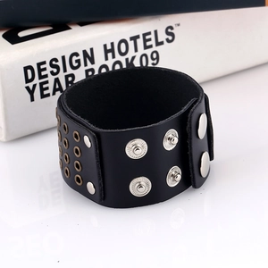 Detail of wide black leather punk bracelet featuring silver studs and metal grommets