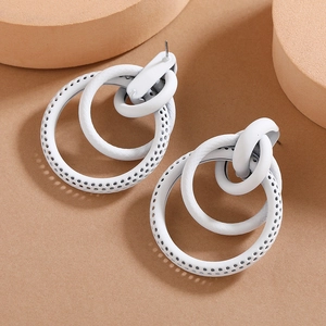 Macro detail of white geometric layered hoop earrings with hollow punch textures