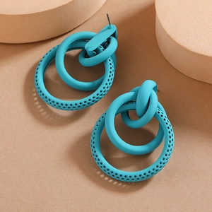 Macro shot of teal geometric round earrings featuring nested rings and perforated detail