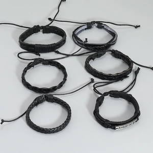 Detailansicht der 6-teiligen schwarzen Lederarmbänder mit 'achieve' Metallplakette