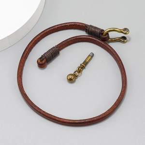 Close-up of brown leather rope with vintage brass U-shaped clasp and screw pin bolt