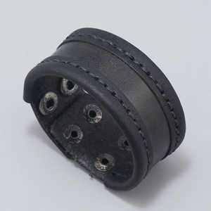 Detail of black leather cuff bracelet featuring dual silver snap buttons and stitched edges