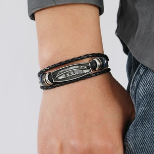 Men's vintage multi-layer braided leather bracelet with silver feather charm on wrist