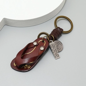 Detail of vintage leather flip-flop keychain with bronze hardware and engraved metal tags