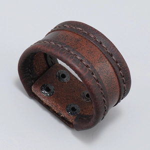 Detail view of brown leather cuff with precise stitching and four gunmetal snap buttons