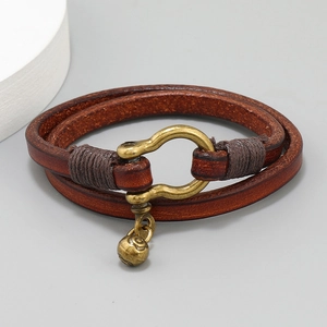 Detail of vintage brown leather wrap bracelet featuring bronze horseshoe clasp and sun charm