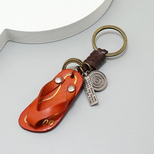 Vintage leather flip-flop keychain with bronze hardware and engraved tag in orange brown