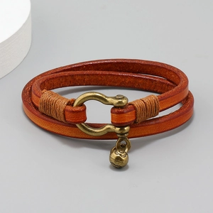 Close-up of double-wrap brown leather bracelet with bronze horseshoe buckle and charm