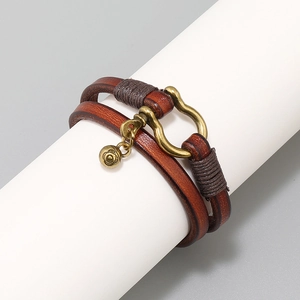 Detail of vintage brown double-wrap leather bracelet with bronze horseshoe buckle and bell