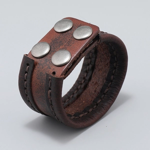 Detail of wide retro brown leather bracelet with silver rivets and hand-stitched edges