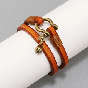 Close-up of vintage caramel leather wrap bracelet with bronze horseshoe buckle and bell