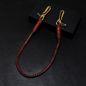 Détail d'une chaîne en cuir tressé marron rouge avec des fermoirs mousquetons en laiton