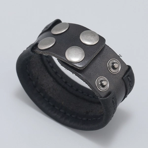 Macro view of black leather bracelet with silver studs and hand-stitched detailing