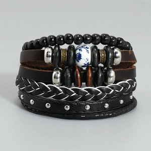 Dettaglio di bracciali in pelle multistrato con cordini intrecciati, borchie e ceramica
