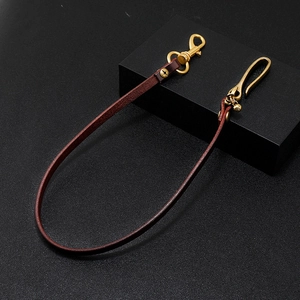 Close-up of a brown leather waist chain with golden metal snap hooks and brass rivets