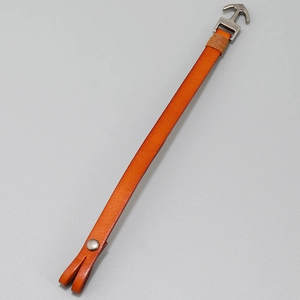 Detail of orange cowhide leather bracelet with silver anchor hook and stitch texture