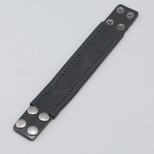 Close-up of black leather cuff bracelet featuring parallel stitching and silver snap buttons