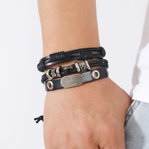 Detail of hand-woven black leather bracelet set with retro metal charms on male wrist