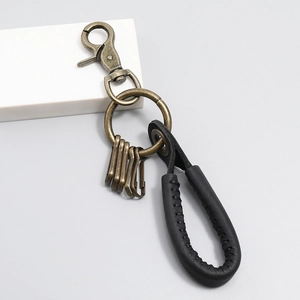 Close-up of vintage bronze lobster clasp and black leather braided keychain detail