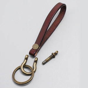 Handmade burgundy leather keychain with antique bronze hardware on a gray background