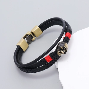 Détail de bracelet en cuir multicouche avec crâne en bronze et accents de fil rouge