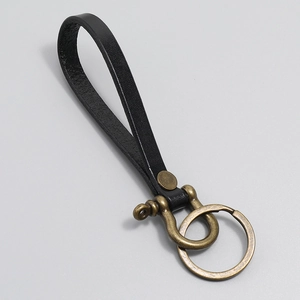 Close-up of black leather strap with antique bronze D-ring and metal key ring detail