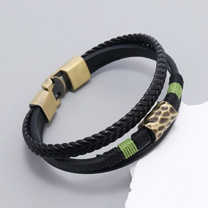 Macro shot of multi-layer black leather bracelet with bronze magnetic clasp on grey stone