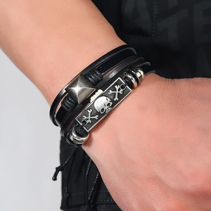 Detail of multi-layer leather bracelet featuring a silver skull plate and metal rivets