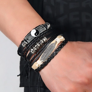Detail of multi-layer leather bracelet set with Yin Yang charm and feather pendant detail
