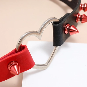 Detail of red studded leather choker with silver heart ring and punk spikes