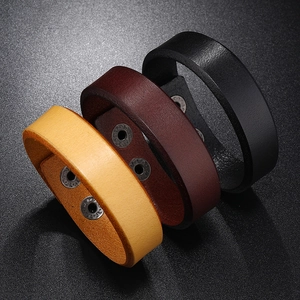 Three vintage punk style leather bracelets in black, brown, and yellow with metal rivets