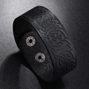 Close-up of black leather bracelet featuring embossed Celtic knot and silver snap buttons