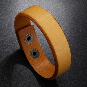 Close-up of brown leather wide bracelet with decorative metal snap buttons and texture