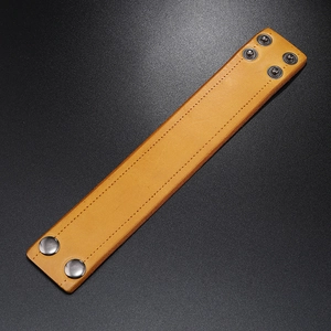 Detail of light brown wide leather bracelet with durable stitching and adjustable metal snaps