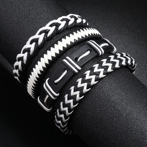 Macro detail of men's multilayer punk braided leather bracelets in black and white