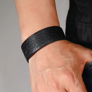 Close-up of black wide leather bracelet featuring embossed Celtic knot patterns