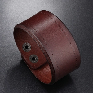 Detail of dark brown leather cuff bracelet with rustic grain and snap button closure
