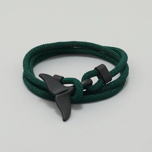 Macro detail of dark green woven nautical rope bracelet with matte black whale tail clasp