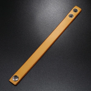 Detail view of yellow leather bracelet with textured surface and adjustable metal snaps