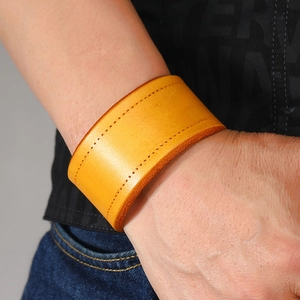 Detail of yellow genuine leather wide bracelet with stitching on model's wrist