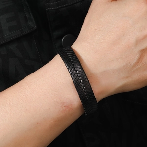 Detail of black herringbone braided leather bracelet on male wrist with matte texture