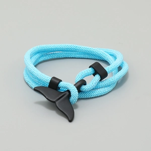 Close-up of blue braided cord bracelet featuring a matte black whale tail clasp detail
