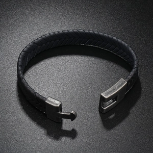 Detail of men's braided leather bracelet with vintage metal clasp on a grey surface