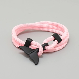 Detail of pink woven Milan rope bracelet featuring a matte black whale tail charm closure