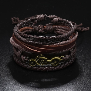Close-up of vintage multi-layer braided leather bracelets with bronze motorcycle charm