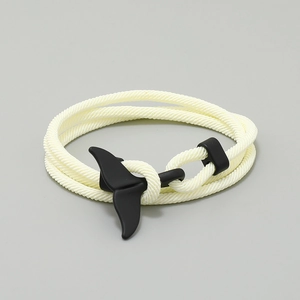 Close-up of cream woven triple-wrap bracelet with a matte black whale tail clasp