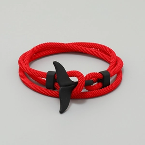 Close-up of red woven cord bracelet with black matte whale tail clasp on grey background