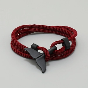 Close-up of deep red braided rope bracelet with a matte black whale tail clasp detail